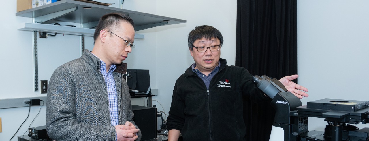 Drs. Sun and Diao look at a microscope in a laboratory in the Vontz Center