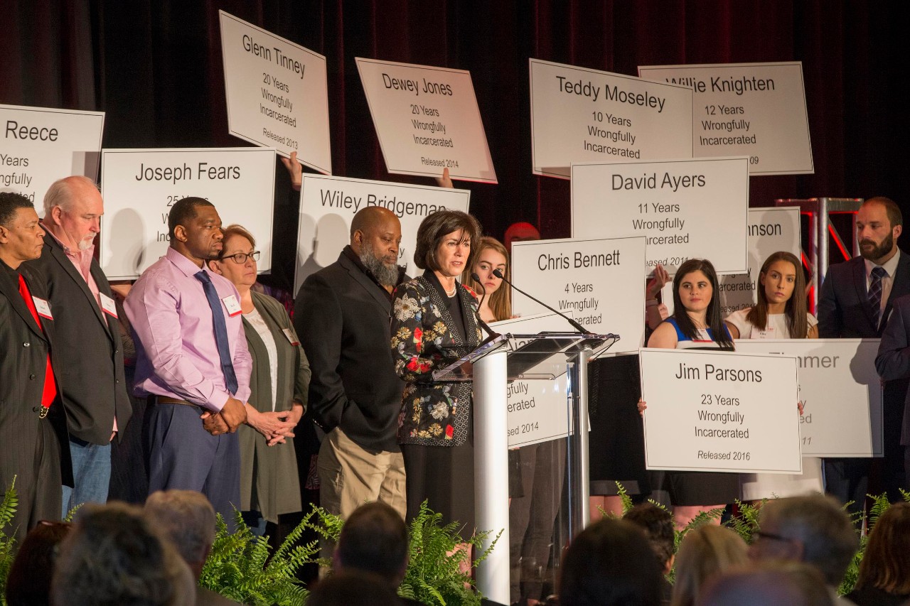 Ohio Innocence Project Breakfast event featuring exonerees with signs showing exoneree names and the years in prison they served