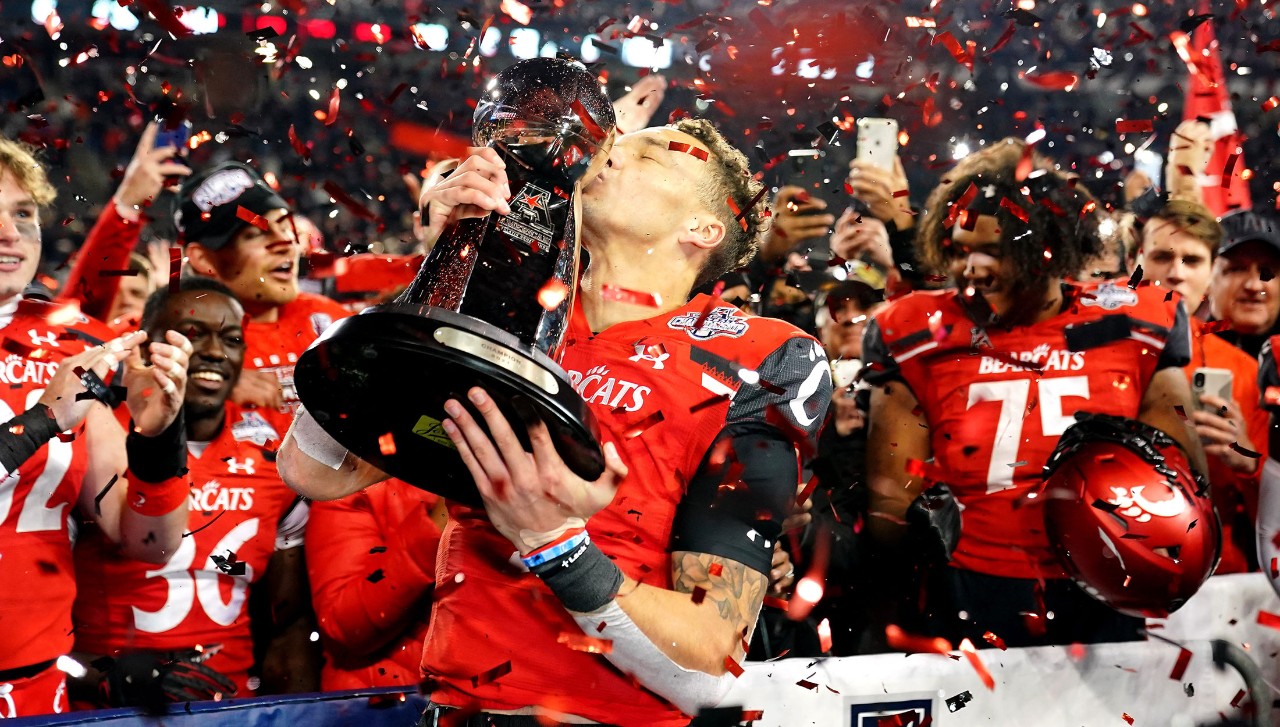 a photo of football players holding a trophy with confetti in the air