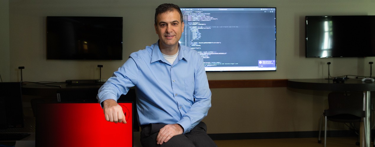 Murat Ozer in front of a screen with computer code