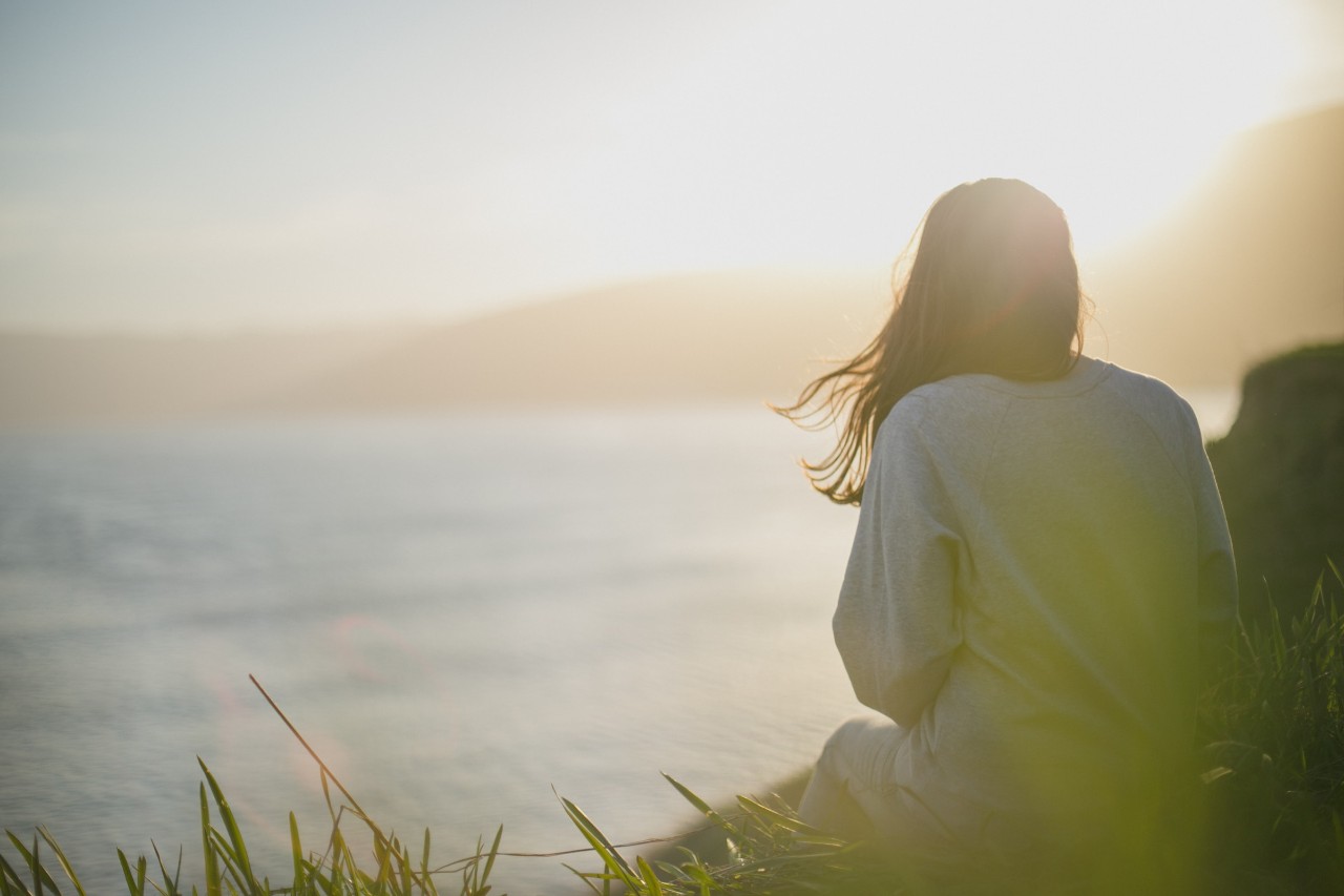 woman sitting on a rock looking at the mountains