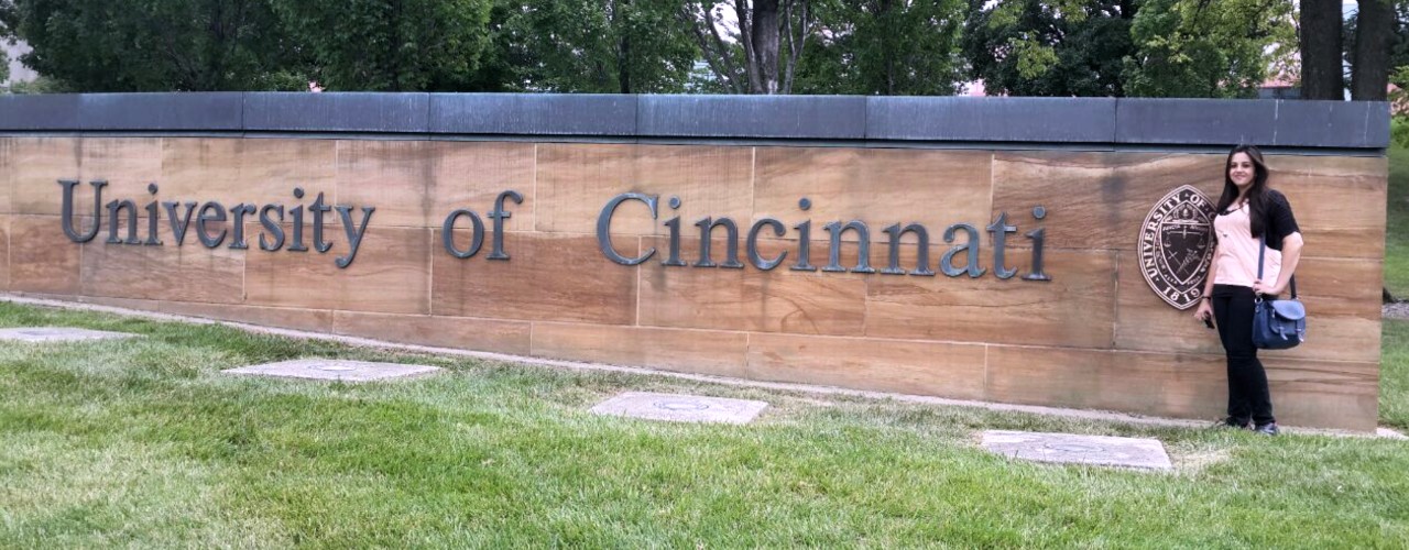 UC DAAP alum Saakshi Terway stands alongside UC entrance wall.