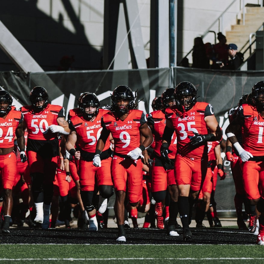 a photo of UC football players taking the field