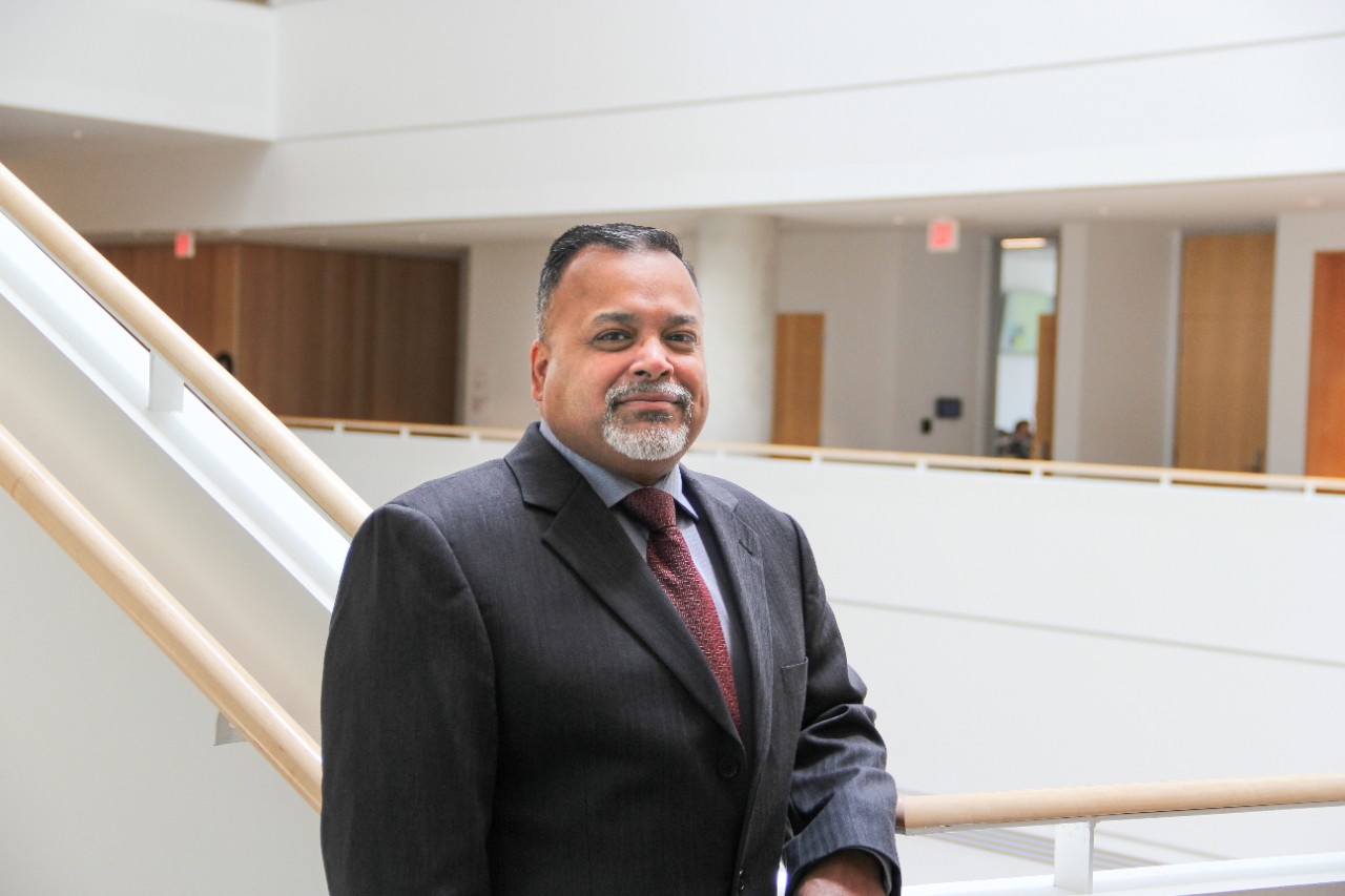Sachin Modi stands next to a staircase overlooking the atrium of Lindner Hall.
