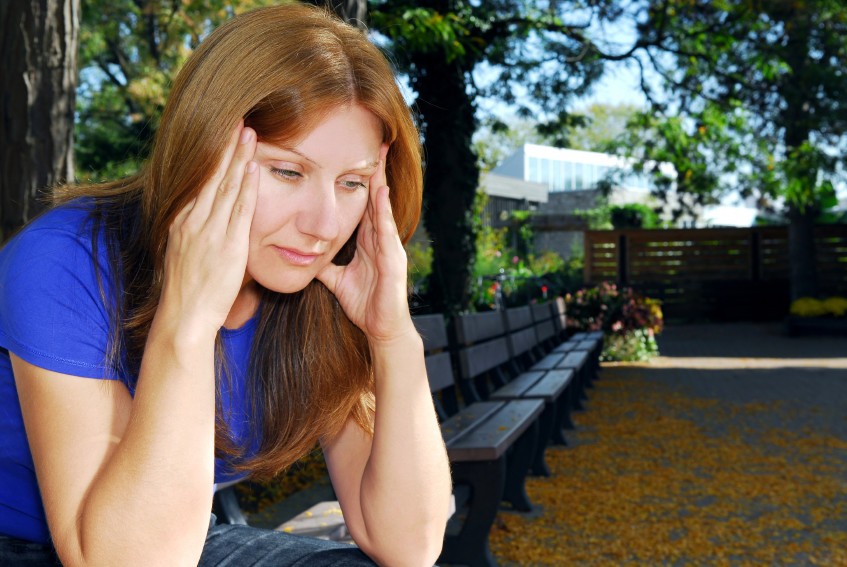 a woman with headache pain holds her hands to her head with her eyes closed