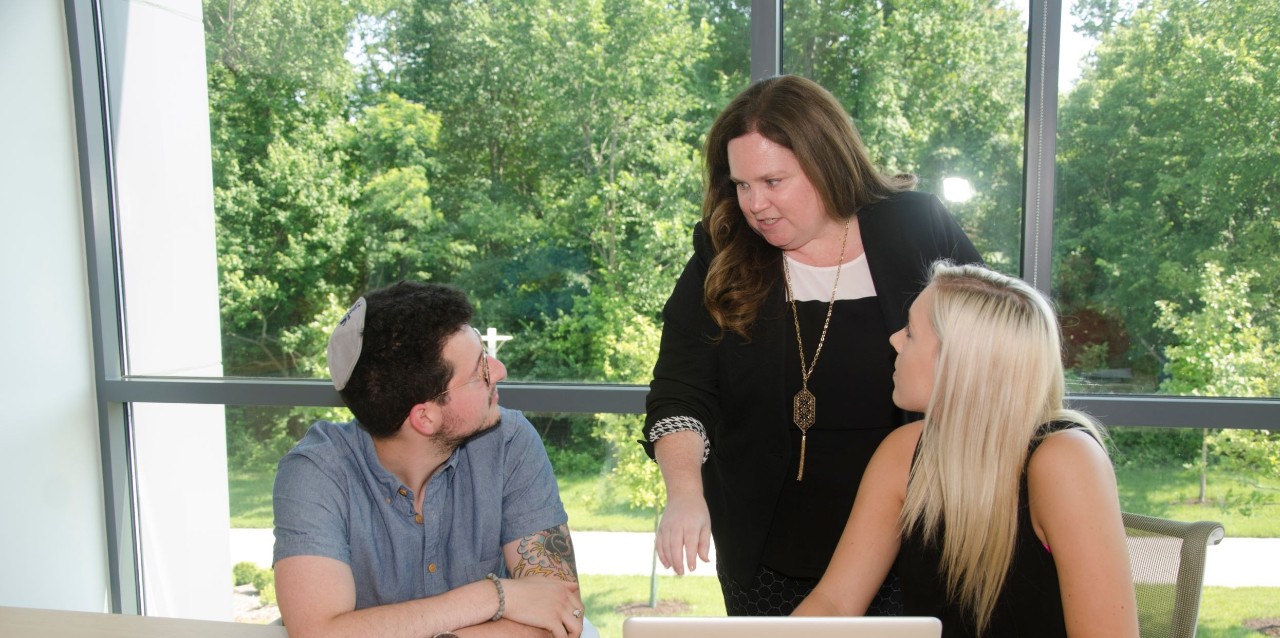 Criminal justice researcher Wendy Calaway standing behind two students and instructing them