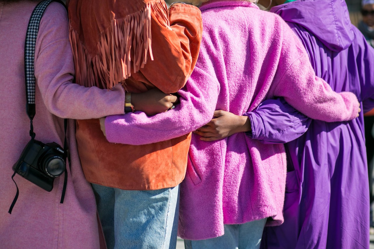 four women from the back view holding arms around each other