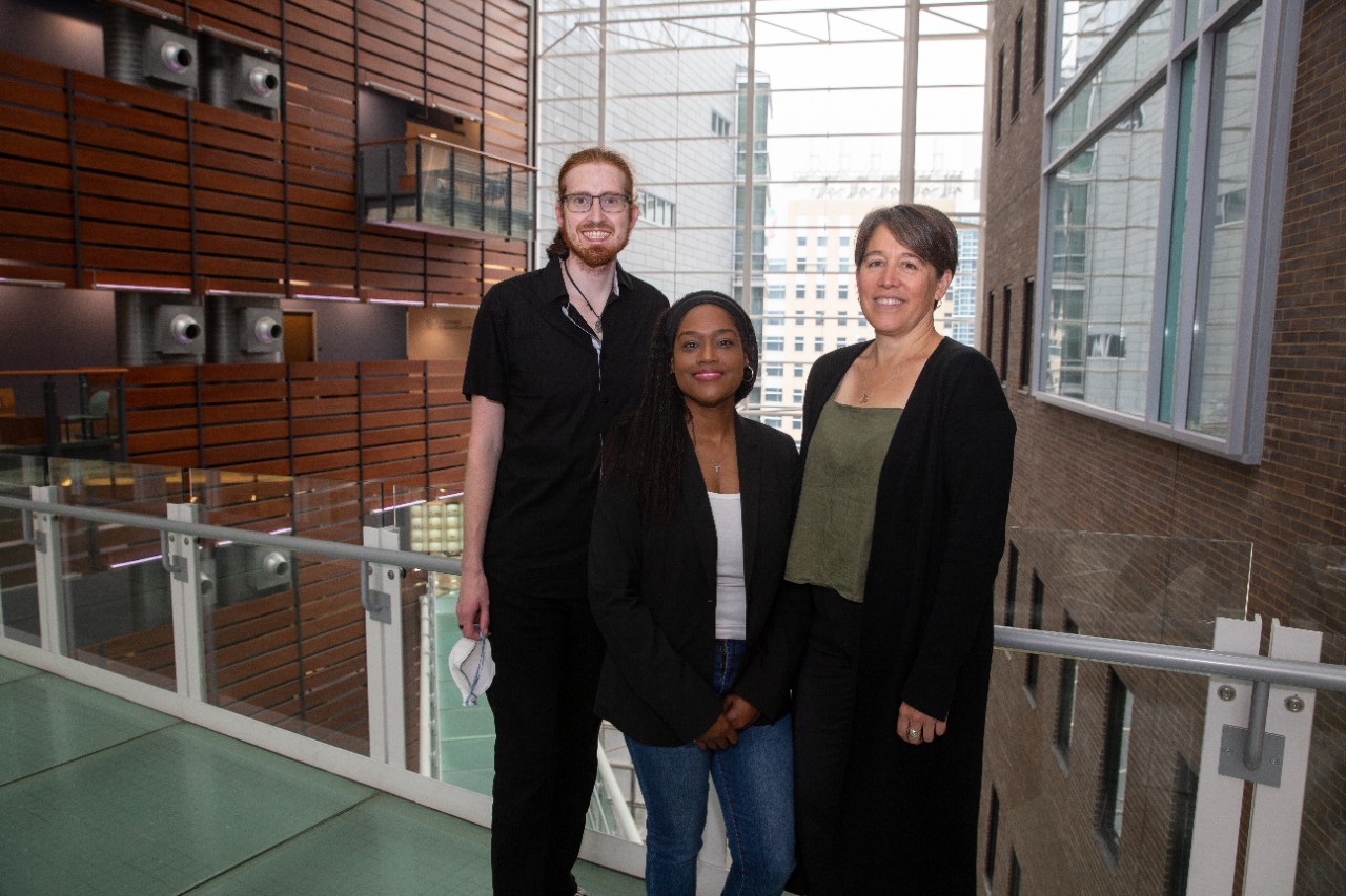 a student researcher and two female professors standing in a college of medicine 