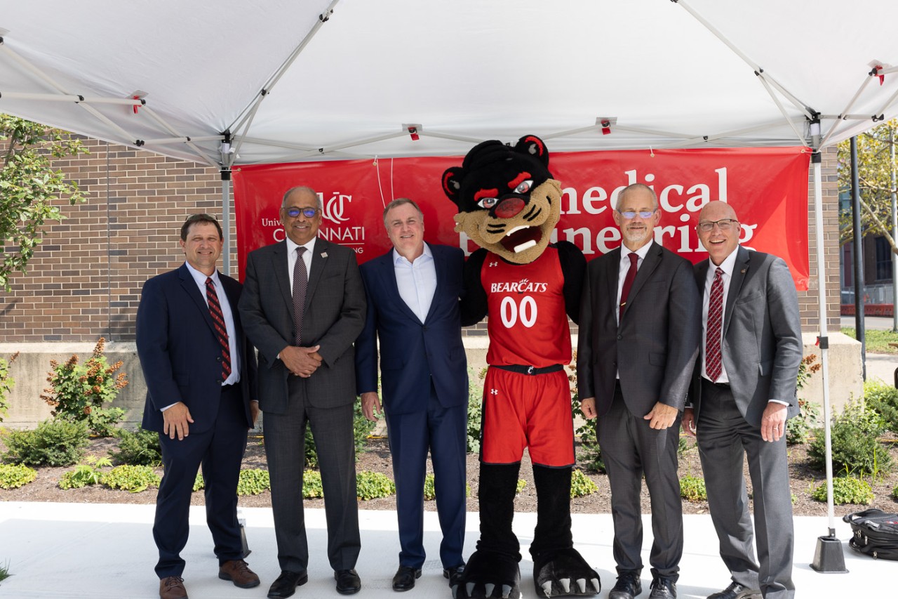 UC dignitaries stand with the Bearcat mascot in front of a banner that says Biomedical Engineering.