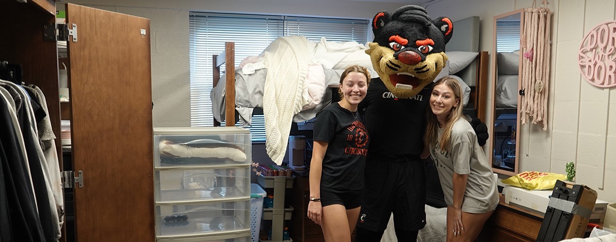 Two students at UC in their dorm room with the Bearcat mascot