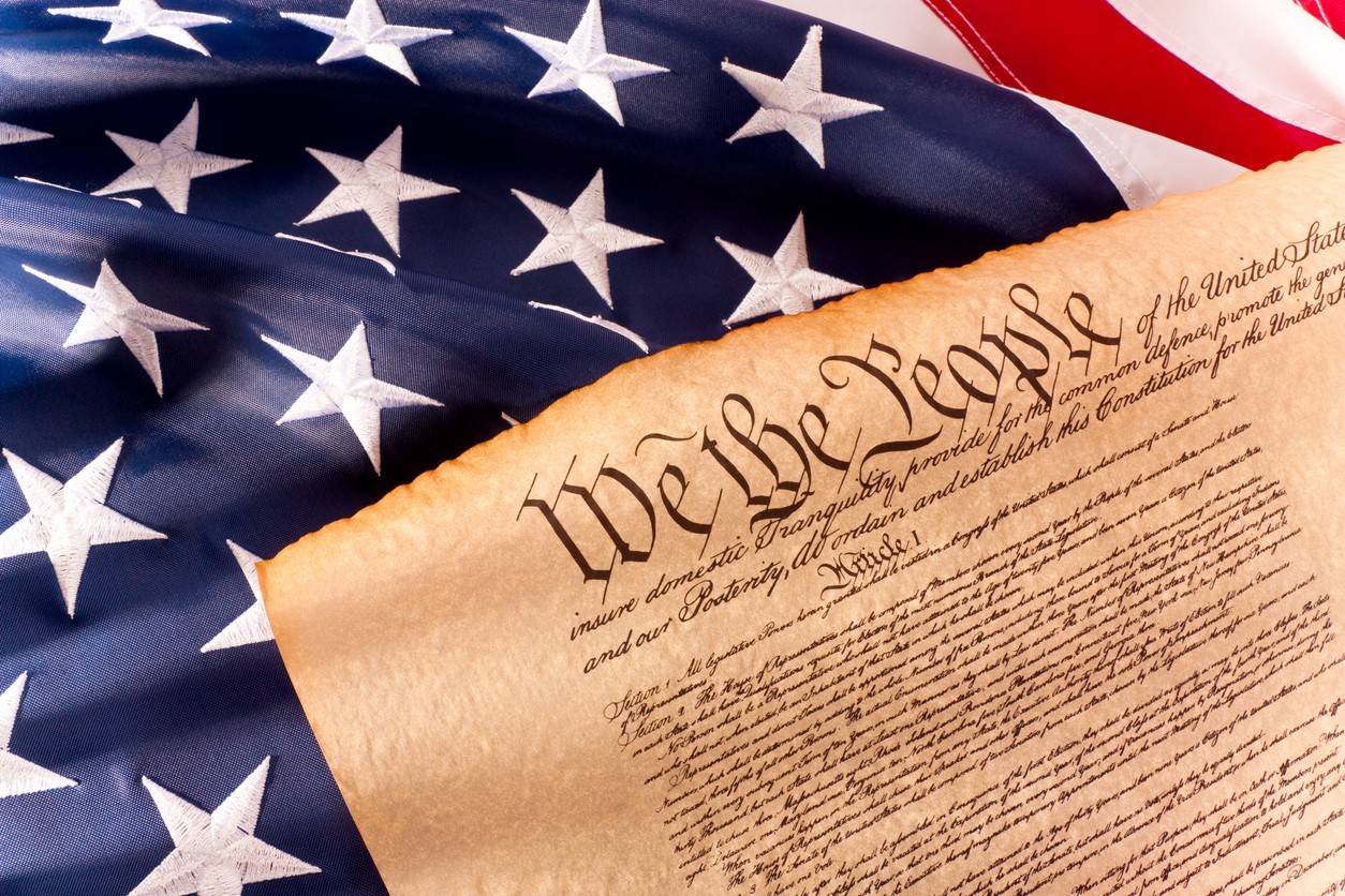 Photo of the US Constitution overlaying the American flag