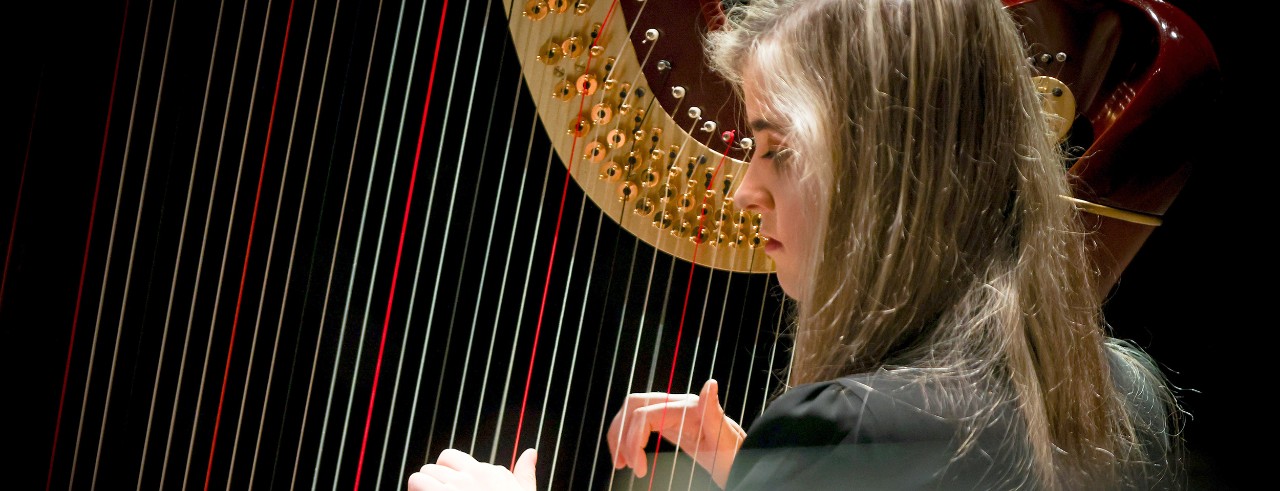 A student harpist performs on stage at UC's College-Conservatory of Music