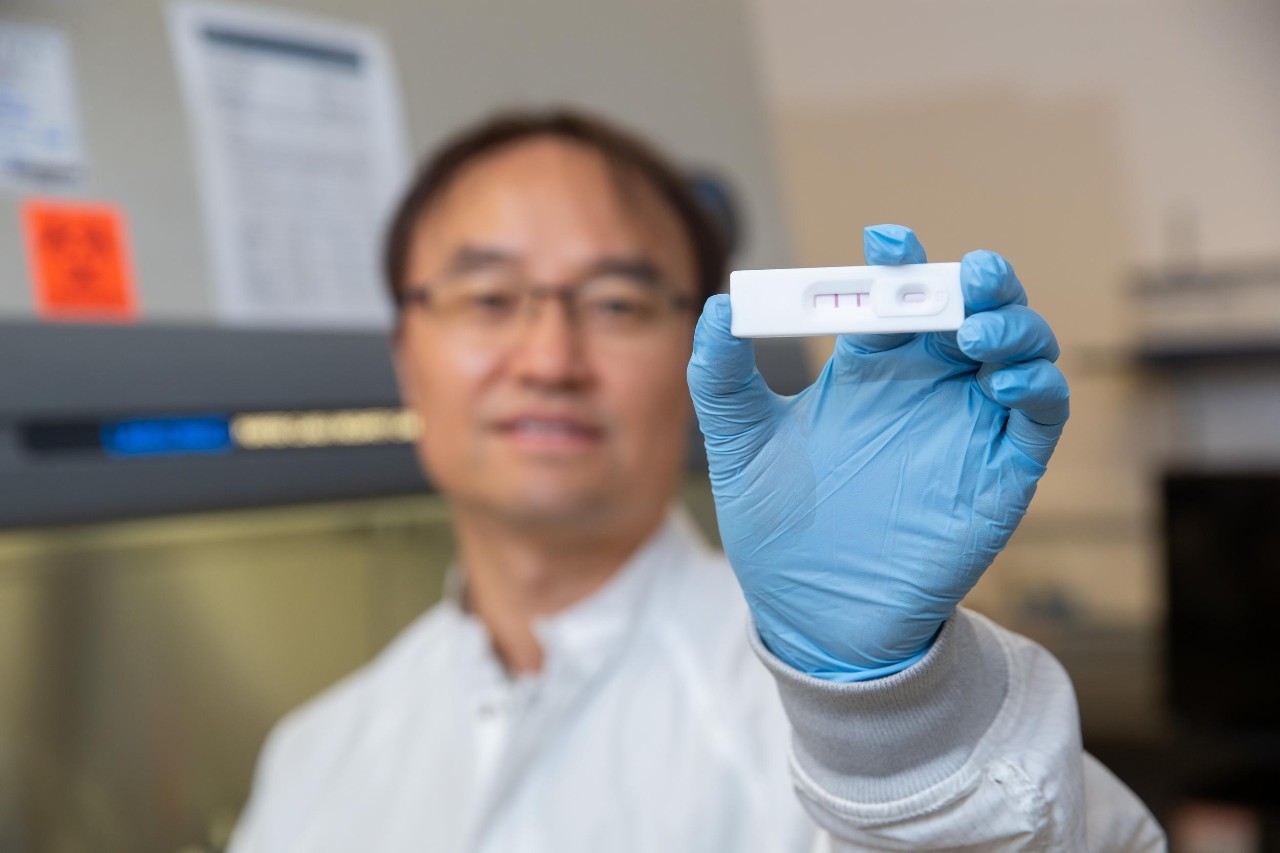 UC Senior Research Associate Daewoo Han holds up an at-home test for periodontal disease in an engineering lab.