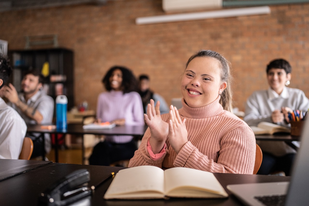 student with down syndrome in the college classroom with classmates 