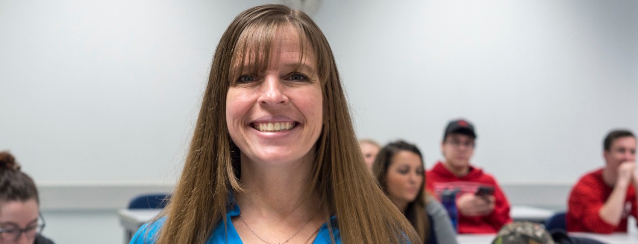 UC Clermont Patty Goedl smiles in front of classroom full of students.