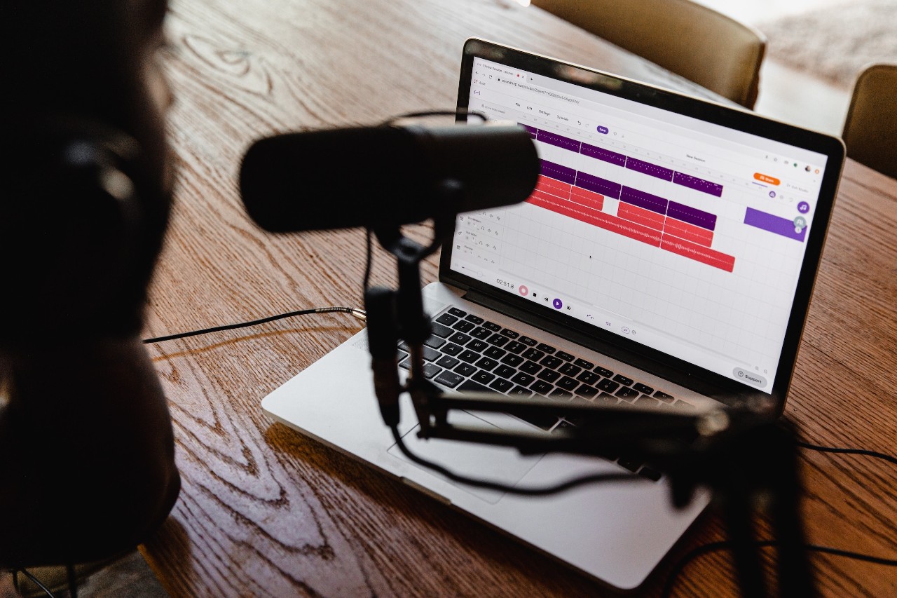 Person recording a podcast with microphone and laptop