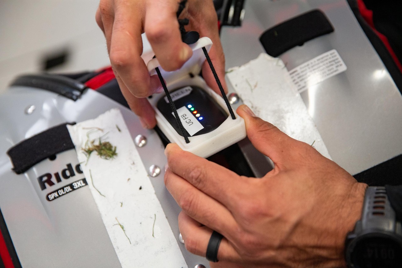 Brandon Garcia, UC's Assistant Director of Football Sports Performance demonstrates the devices football players wear to measure their performance during practices and games. UC's Digital Fabrication Lab came up with custom cases to protect the sensors.