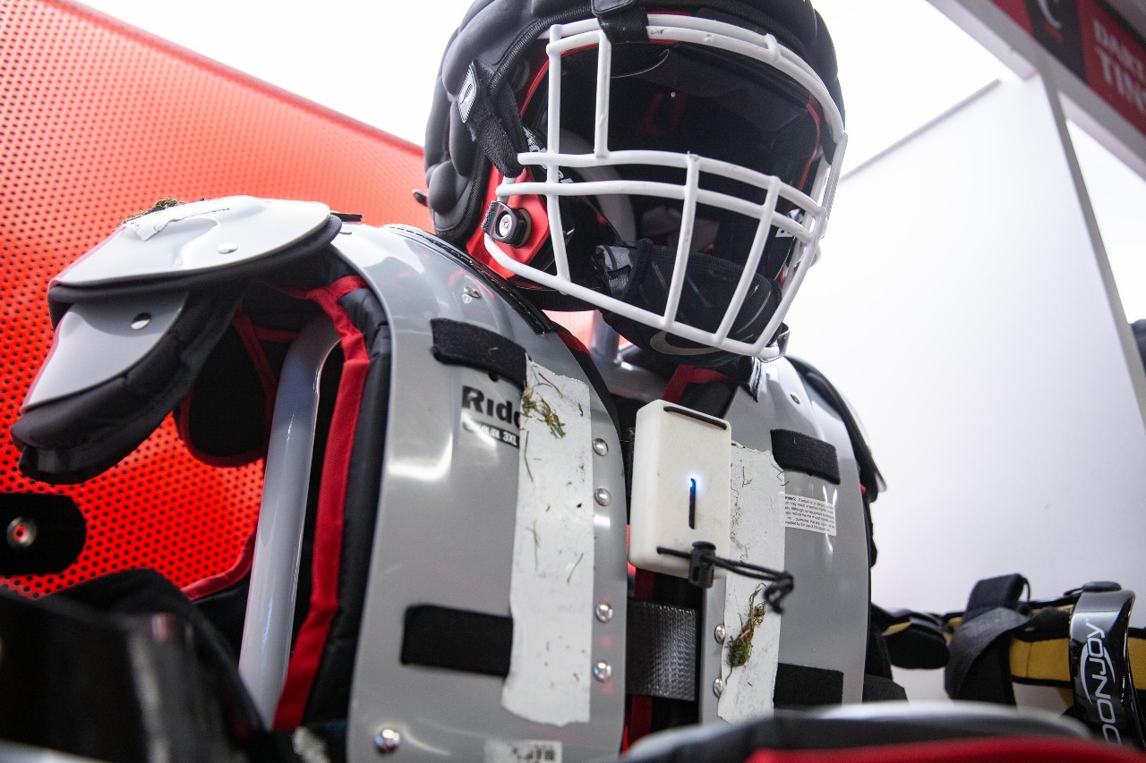 Brandon Garcia, UC's Assistant Director of Football Sports Performance demonstrates the devices football players wear to measure their performance during practices and games. UC's Digital Fabrication Lab came up with custom cases to protect the sensors.