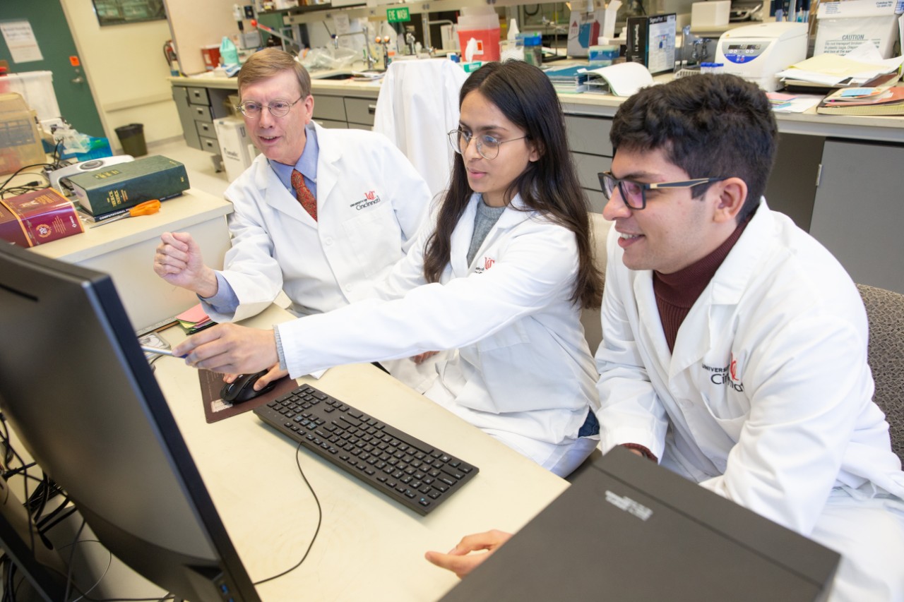 a faculty researcher reviews data on a computer with two student researchers