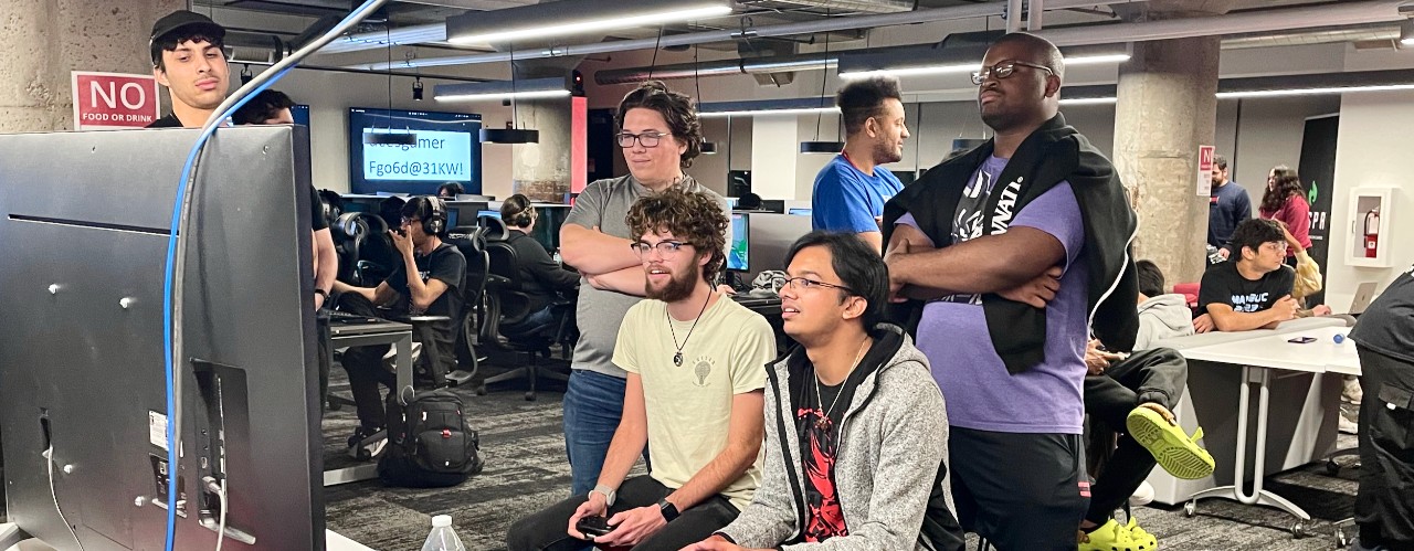 College students stand around a large video game screen in UC's ESports Innovation Lab in the 1819 Innovation Hub.