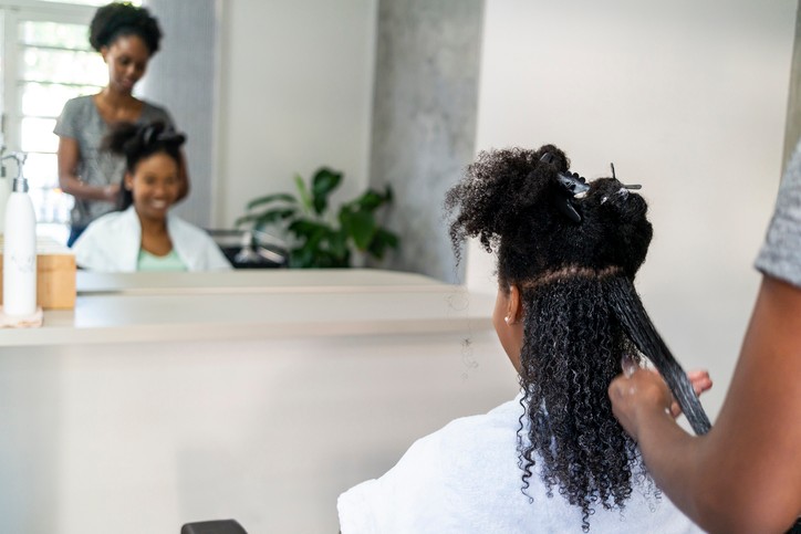 A hair stylist straightens a woman's hair