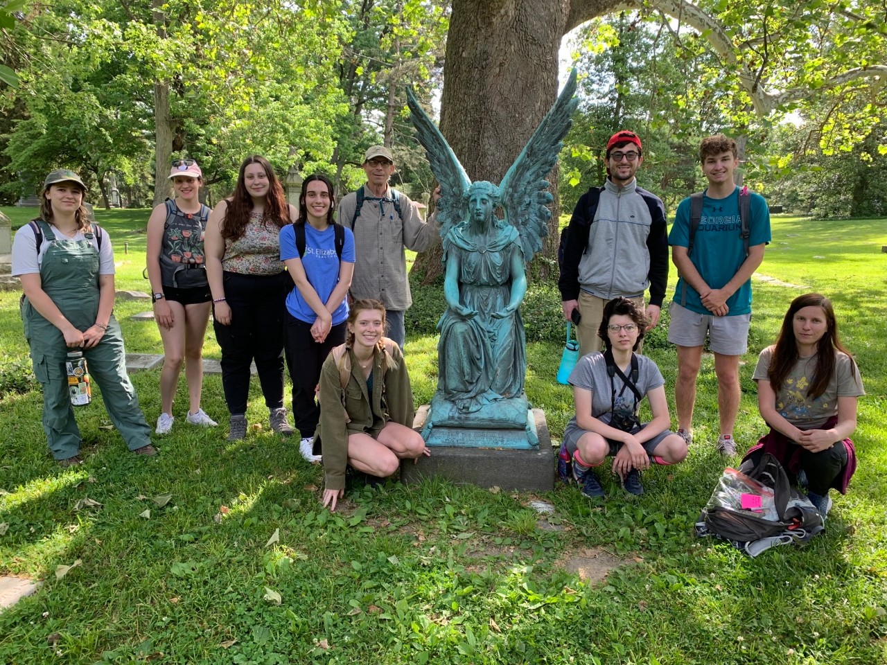 Denis Conover and his students stand next to an angel statue at Spring Grove Cemetery.