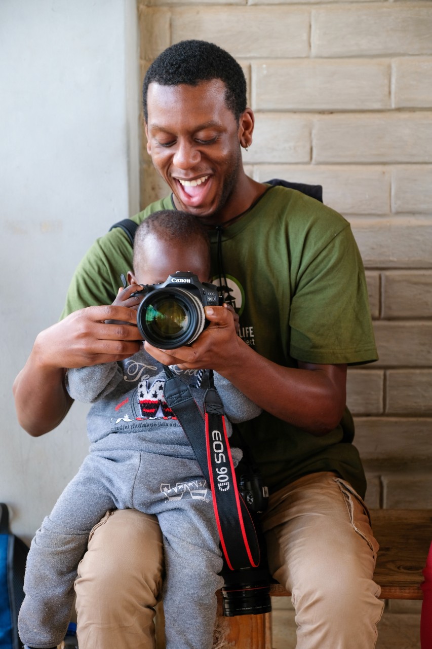 Frank Bowen with baby on lap holding camera