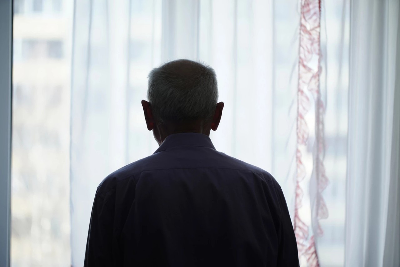 a photo of a man's silouhette from behind looking out a window