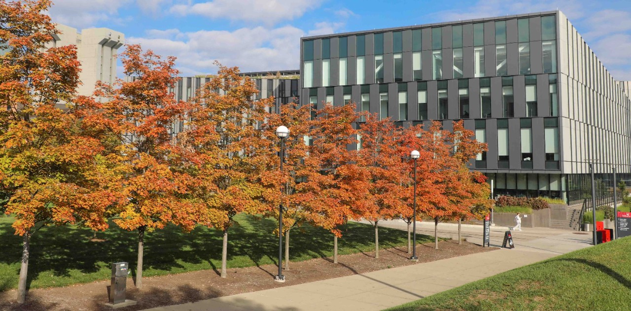 The exterior of Lindner Hall is shown with autumn-colored trees in the foreground.