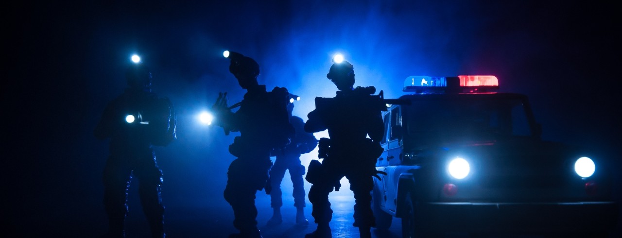 night time photograph of police SWAT team outside with lights glaring