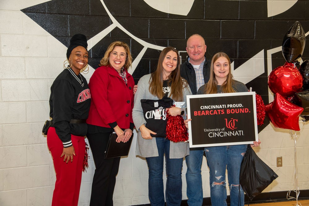 A group of parents and administrators posing with student and Bearcat mascot in school