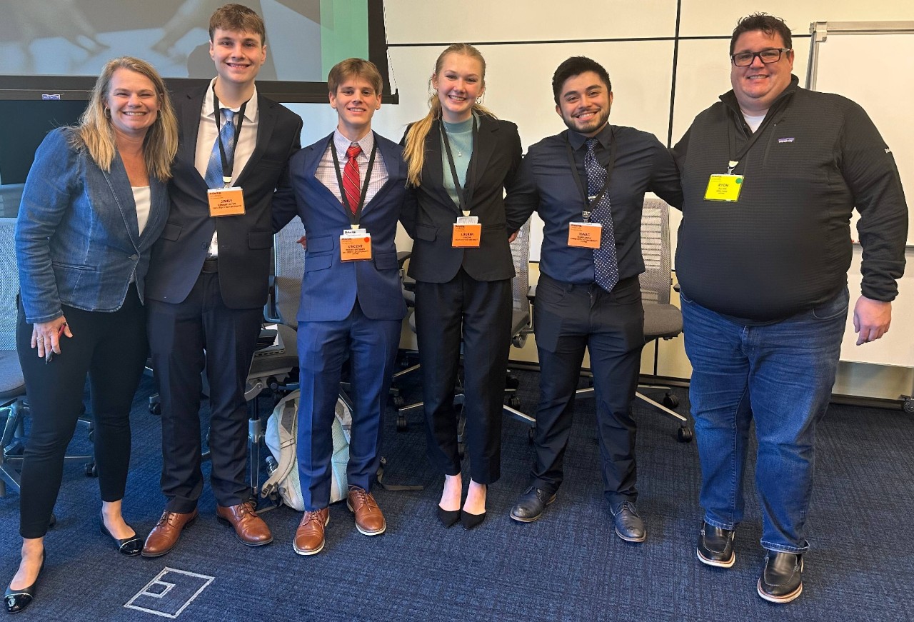 Four Lindner students pose with two Deloitte employees. Students wearing dark professional dress.