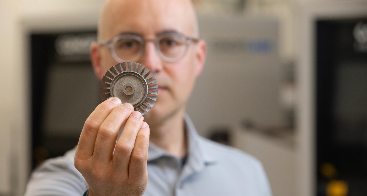 Associate Professor Eric Payton holds up a turbine made through additive manufacturing.