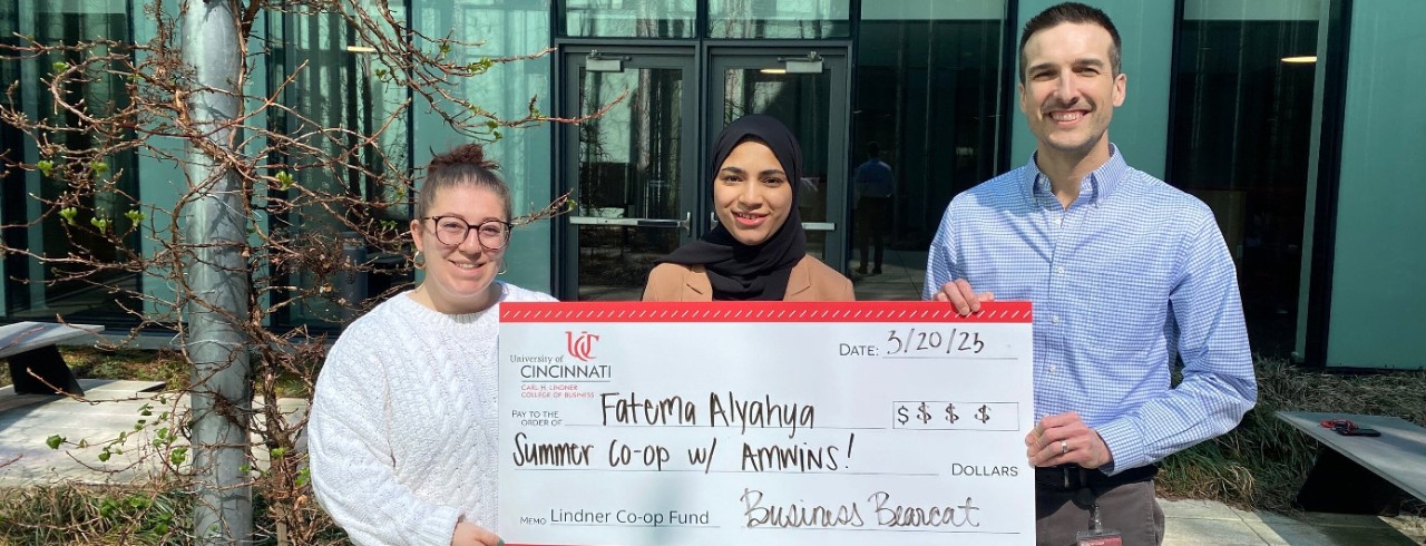 Assistant Director of Lindner Career Services Bella Gullia (left), Lindner student Fatema Alyahya (center) and Michael Nuttle (right), assistant director of Lindner Career Services, pose with an oversized check