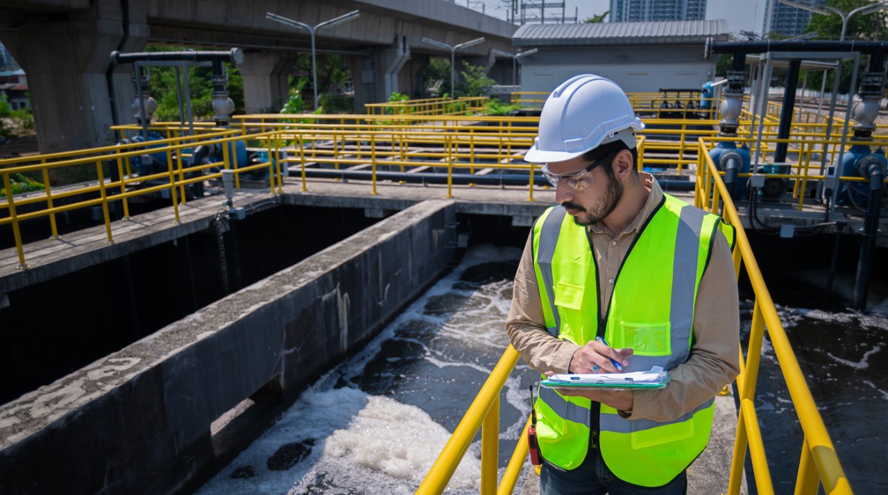 An engineer examines a wastewater treatment pond.