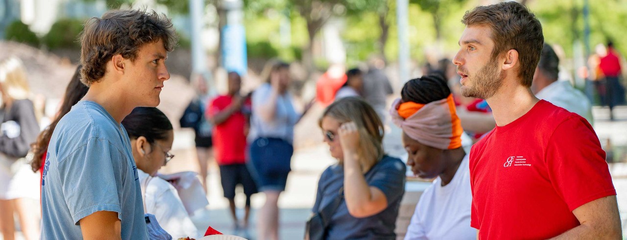 Assistant Director of Career Development Charlie Thornton speaks with a UC student at an outdoor event.