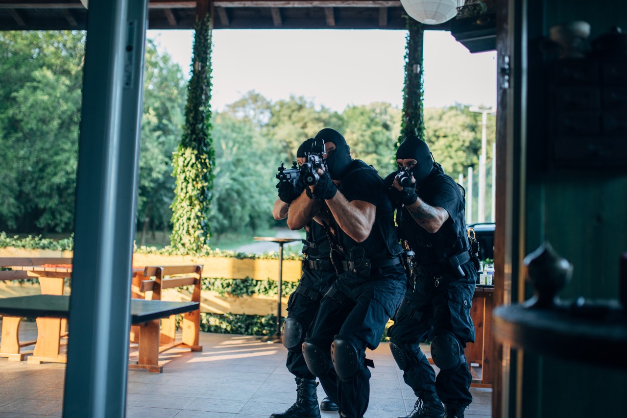 Three masked police officers entering a home