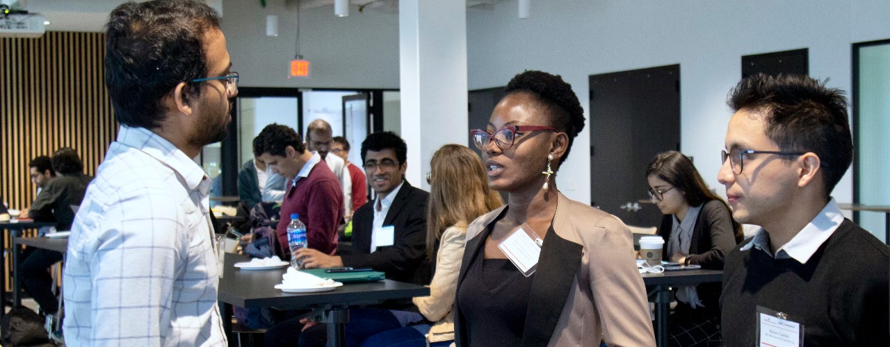 Crowd of students sit in UC's 1819 Innovation Hub listening to a speaker at a podium.