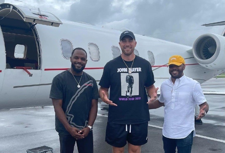 Andre Eanes, Travis Kelce and Aaron Eanes stand in front of a jet. 