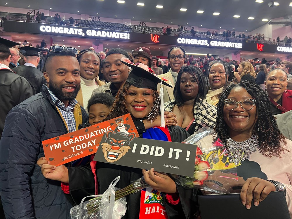 Nadege Mondesir wears a cap and gown and celebrates with her family at her commencement ceremony