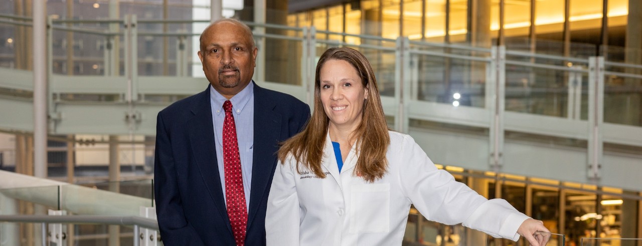 Drs. Desai and Wise-Draper stand and smile on a bridge in UC's CARE/Crawley Building