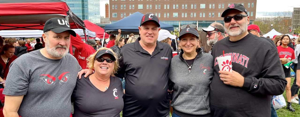Randal Houts on left stands with friends at Bearcat football tailgate on UC campus.