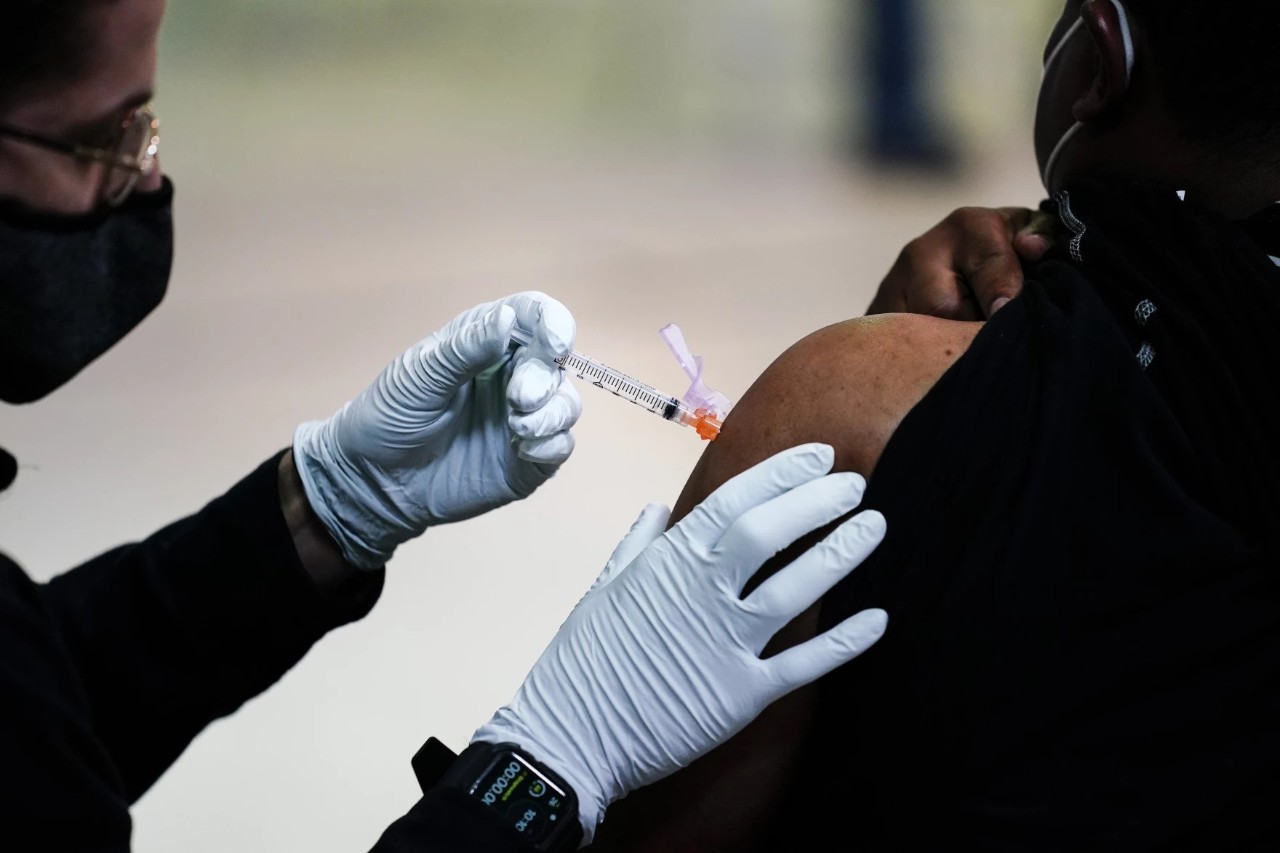 a person wearing a mask giving a vaccine
