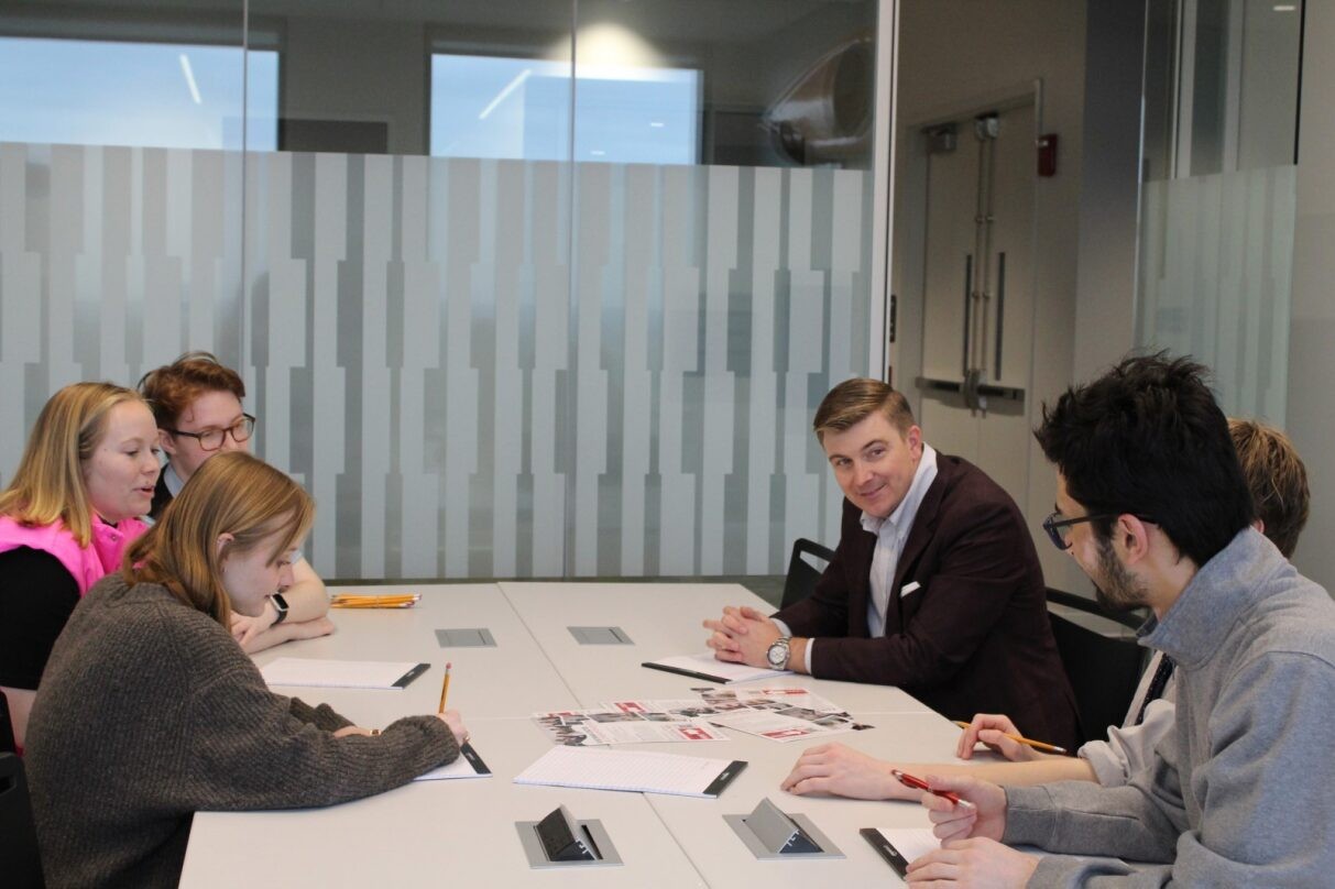 UC Professor Andrew Lewis with students in a classroom.