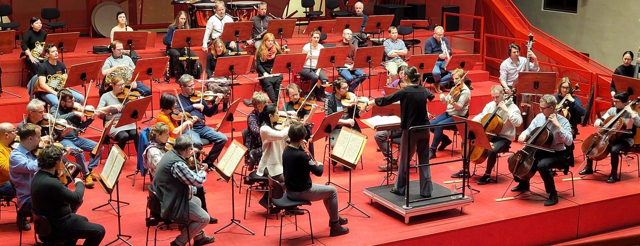 Chaowen Ting conducting an orchestra on stage.