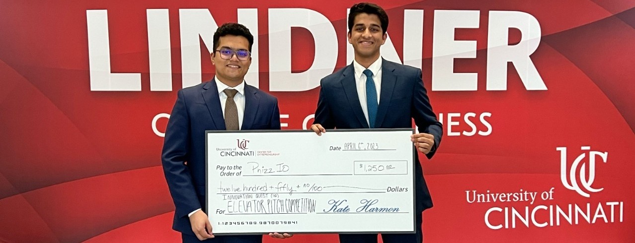 Joe Kuncheria Panjikaran and Aniruddhan Ramesh hold a large check following a pitch competition at the Lindner College of Business.