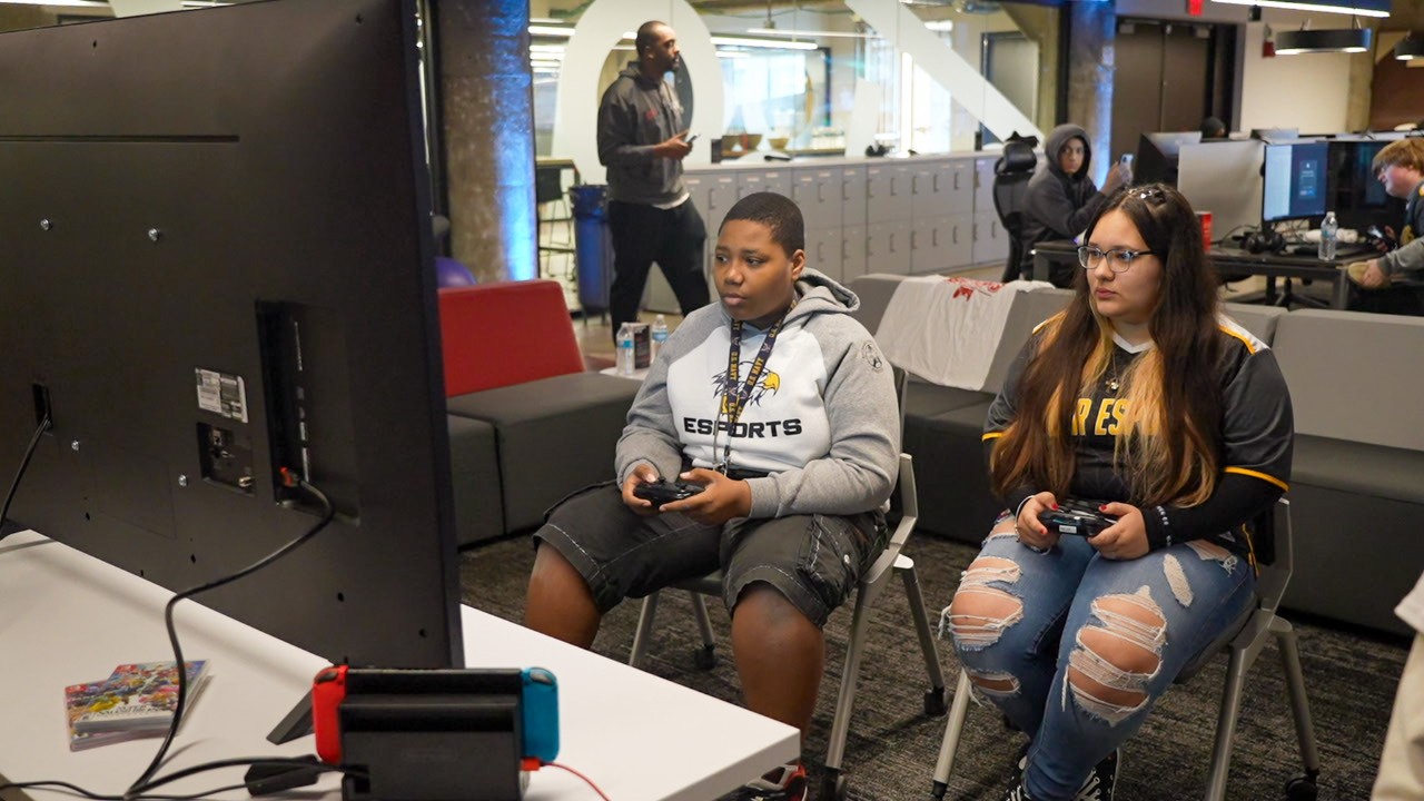 Two students play a video game in a computer lab.