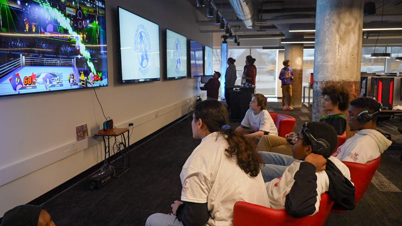 Students seated around a television screen play a video game.