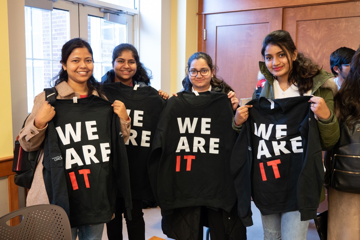 Four women hold T-shirts that have the words "We are IT" on them.