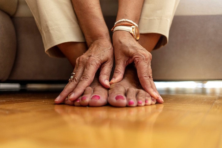 A woman massages her feet with her hands 
